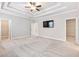 Bright main bedroom with ceiling fan, TV, tray ceiling, and carpet at 4905 Sterling Close, Buford, GA 30518