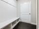 Mudroom with dark wood flooring, white bench with storage, coat hooks, and a white door at 4905 Sterling Close, Buford, GA 30518