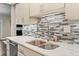 Modern kitchen featuring a double sink, mosaic tile backsplash, and bright white marble countertops at 505 Ansley Villa Dr, Atlanta, GA 30324