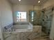 A view of the soaking tub and frameless glass shower in the new primary bathroom at 508 Healy Dr # 70, Cumming, GA 30040