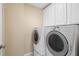 Bright laundry room featuring a white washer and dryer set, with white cabinetry above at 11945 Dancliff Trce, Alpharetta, GA 30009
