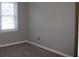 A bedroom featuring a window with white trim, gray colored walls, and beige carpeting at 2031 Lakewood Cir, Grayson, GA 30017