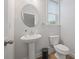 Modern powder room with a pedestal sink, oval mirror, and natural light from the window at 730 Lanarck Way, Peachtree City, GA 30269