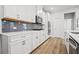 Bright kitchen features white cabinets, stainless steel appliances, gray backsplash, and wood flooring at 730 Lanarck Way, Peachtree City, GA 30269