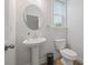 This powder room features a pedestal sink, oval mirror, and natural light at 730 Lanarck Way, Peachtree City, GA 30269