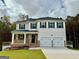 Two-story home boasts a covered front porch, two-car garage, and manicured lawn on a wooded lot at 748 Great Oak Pl, Villa Rica, GA 30180