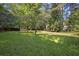 Large grassy backyard with mature trees and a small outbuilding at 1111 Louise Se Ct, Conyers, GA 30013