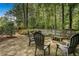 Backyard with a stone patio, seating area, and play set, surrounded by lush trees and a wooden fence at 5015 Preservation Pointe Nw, Kennesaw, GA 30152