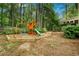 View of a backyard with a wooden playset with slide and swing in a green, tree-filled setting at 5015 Preservation Pointe Nw, Kennesaw, GA 30152