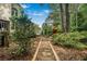 Landscaped backyard featuring a walking path leading to a play set, mature trees, and lush greenery at 5015 Preservation Pointe Nw, Kennesaw, GA 30152