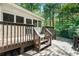 Exterior shot of a spacious wooden deck featuring steps, a sunroom, and a backdrop of lush green trees at 5015 Preservation Pointe Nw, Kennesaw, GA 30152