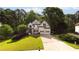 Charming two-story home with a manicured lawn, mature trees, and a spacious driveway leading to a three-car garage at 5015 Preservation Pointe Nw, Kennesaw, GA 30152