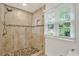 Elegant tiled shower with pebble floor, glass door, and window bringing in natural light make for a bright and airy bathroom at 4140 Summit Dr, Marietta, GA 30068