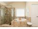The clean bathroom boasts a tub, a walk-in shower with glass and decorative tile, next to a sunny window at 5888 Cobblestone Creek Cir, Mableton, GA 30126