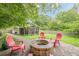 Backyard stone fire pit with Adirondack chairs, lush green lawn, and screened in porch at 2497 Edwards Nw Dr, Atlanta, GA 30318