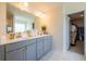 Bright bathroom with a double sink vanity, gray cabinets, gold hardware, and a large mirror at 13568 Scenic Pkwy, Covington, GA 30014