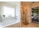 Bright bathroom with a bathtub, shower, and window with natural light at 13568 Scenic Pkwy, Covington, GA 30014