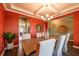 An open dining room with red walls, modern lighting, seating for six, and hardwood flooring at 13568 Scenic Pkwy, Covington, GA 30014