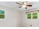 Bedroom with a ceiling fan, two windows looking out into the trees, and neutral-colored walls at 211 Caboose Ln, Woodstock, GA 30189