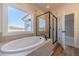 Bright bathroom features a large soaking tub, a glass shower, and a view of the pasture at 257 Pinewood Dr, Covington, GA 30014