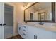 Well-lit bathroom vanity with dual sinks, framed mirror, white cabinets, and black hardware at 257 Pinewood Dr, Covington, GA 30014