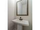 Powder room featuring white pedestal sink and black faucet beneath a framed mirror at 257 Pinewood Dr, Covington, GA 30014