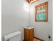 Small bathroom with toilet, sink, a window, and textured walls at 3060 Robertswood Dr, Powder Springs, GA 30127