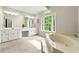 Luxurious main bathroom with soaking tub, vanity area, and abundant natural light at 3060 Robertswood Dr, Powder Springs, GA 30127