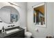 Modern bathroom with a round mirror, black fixtures, and a sleek vanity with black countertop at 3740 Powers Ferry Nw Rd, Atlanta, GA 30342