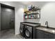 Well-organized laundry room features a sink, modern appliances, shelving and grey cabinets at 3740 Powers Ferry Nw Rd, Atlanta, GA 30342