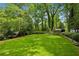 Expansive backyard featuring a lush green lawn, mature trees, and a small outbuilding at 1130 Angelo Ne Ct, Atlanta, GA 30319