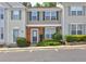 Inviting townhouse featuring a brick facade, green shutters and door, complemented by lush landscaping at 1295 Kilmington Ct, Alpharetta, GA 30009