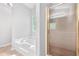 Bright bathroom showcasing soaking tub, and tiled shower with glass door and a gold trim at 9955 Rivertown Rd, Fairburn, GA 30213