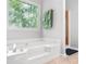 Bright bathroom showcasing a soaking tub with a large window overlooking the green trees outside at 9955 Rivertown Rd, Fairburn, GA 30213