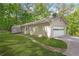 Side view of the home, showcasing the garage, driveway, well-kept lawn and surrounding greenery at 9955 Rivertown Rd, Fairburn, GA 30213