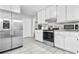 Bright kitchen with stainless steel fridge, oven, and microwave with white cabinets and granite counters at 9955 Rivertown Rd, Fairburn, GA 30213