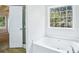 Bright bathroom featuring a soaking tub under a large window and a white door leading to another room at 10 Hollow Ct, Covington, GA 30016