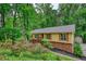 Charming exterior of a yellow home with brown shutters surrounded by lush greenery and trees at 3311 Creek Hollow Dr, Marietta, GA 30062