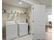 Well-lit laundry room featuring a washer, dryer, and storage shelves at 436 Barnett St, Woodstock, GA 30188