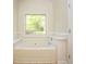 Bright bathroom featuring a large tub with a window overlooking the backyard at 47 Cliff Ct, Villa Rica, GA 30180