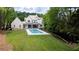 Aerial view of a backyard featuring a modern pool, green grass, and wooded surroundings at 541 Londonberry Rd, Atlanta, GA 30327