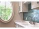 Charming mudroom features custom cabinets, eye-catching tiles, a stylish faucet, and a sunlit oval window at 541 Londonberry Rd, Atlanta, GA 30327
