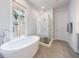Bathroom showcasing white soaking tub, glass shower with tiled walls and gray tile floors at 4046 Hazel Nut Ln, Atlanta, GA 30342