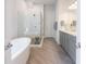 Bathroom featuring gray cabinets, dual vanity, soaking tub, glass enclosed shower and tile floors at 4046 Hazel Nut Ln, Atlanta, GA 30342