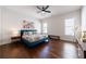 Bright bedroom with dark hardwood floors, ceiling fan and a large blue bed frame and vibrant floral comforter at 4046 Hazel Nut Ln, Atlanta, GA 30342