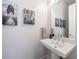 Stylish powder room featuring a pedestal sink, mirror, and modern artwork at 4046 Hazel Nut Ln, Atlanta, GA 30342