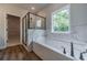 Modern bathroom boasts soaking tub, frameless glass shower, and views of the backyard at 1482 Alcovy Station Rd, Covington, GA 30014
