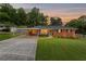 Charming brick home with mature trees, manicured lawn, and covered parking at sunset at 3872 Francis Dr, Powder Springs, GA 30127