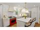 Bright kitchen featuring white cabinets, a red range, an island with marble countertop and pendant lighting at 3872 Francis Dr, Powder Springs, GA 30127