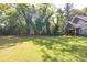 Wide shot of the yard featuring expansive, well-maintained lawn surrounded by mature trees at 399 Chestnut St, Social Circle, GA 30025
